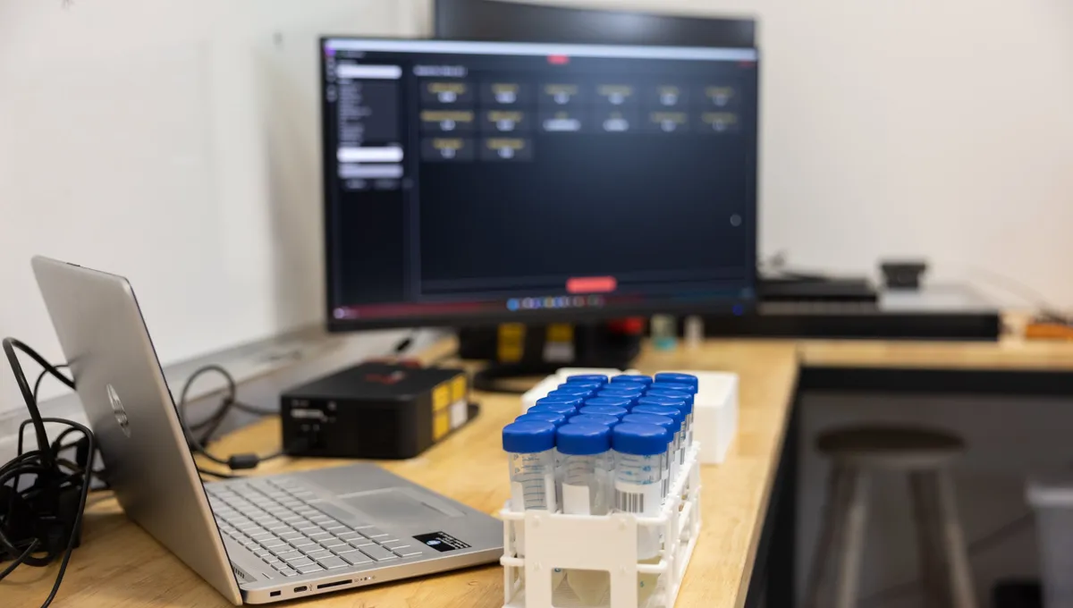 A laptop and results screen beside a Hone Lab Black and a rack of sample vials