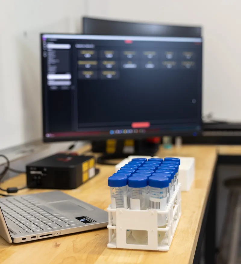 A laptop and results screen beside a Hone Lab Black and a rack of sample vials