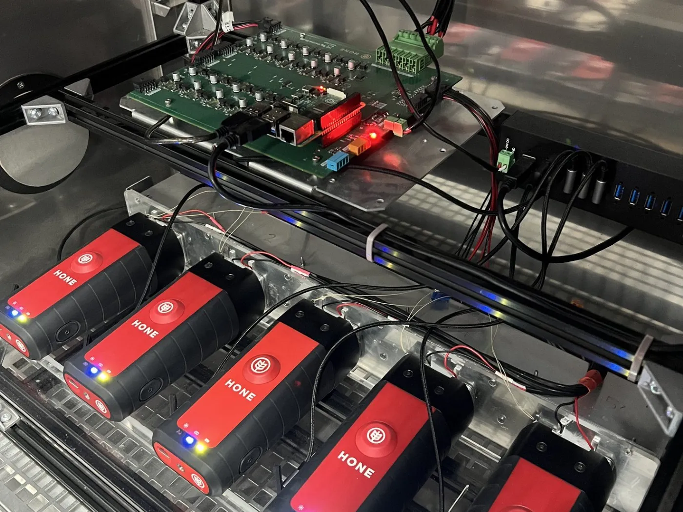 Five Hone Lab Red instruments racked in an environmental test chamber, cabled to a test board